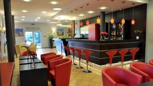 A modern bar area with red bar stools and a black counter. - Hotel Topaz Poznań Centrum (Poznan)