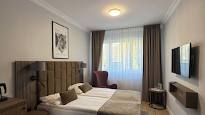 A hotel room with a bed, a desk, a chair, a TV, and a window with curtains. - Hotel Topaz Poznań Centrum (Poznan)