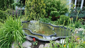 A garden with a pond, surrounded by various plants and rocks. - Hotel Topaz Poznań Centrum (Poznan)