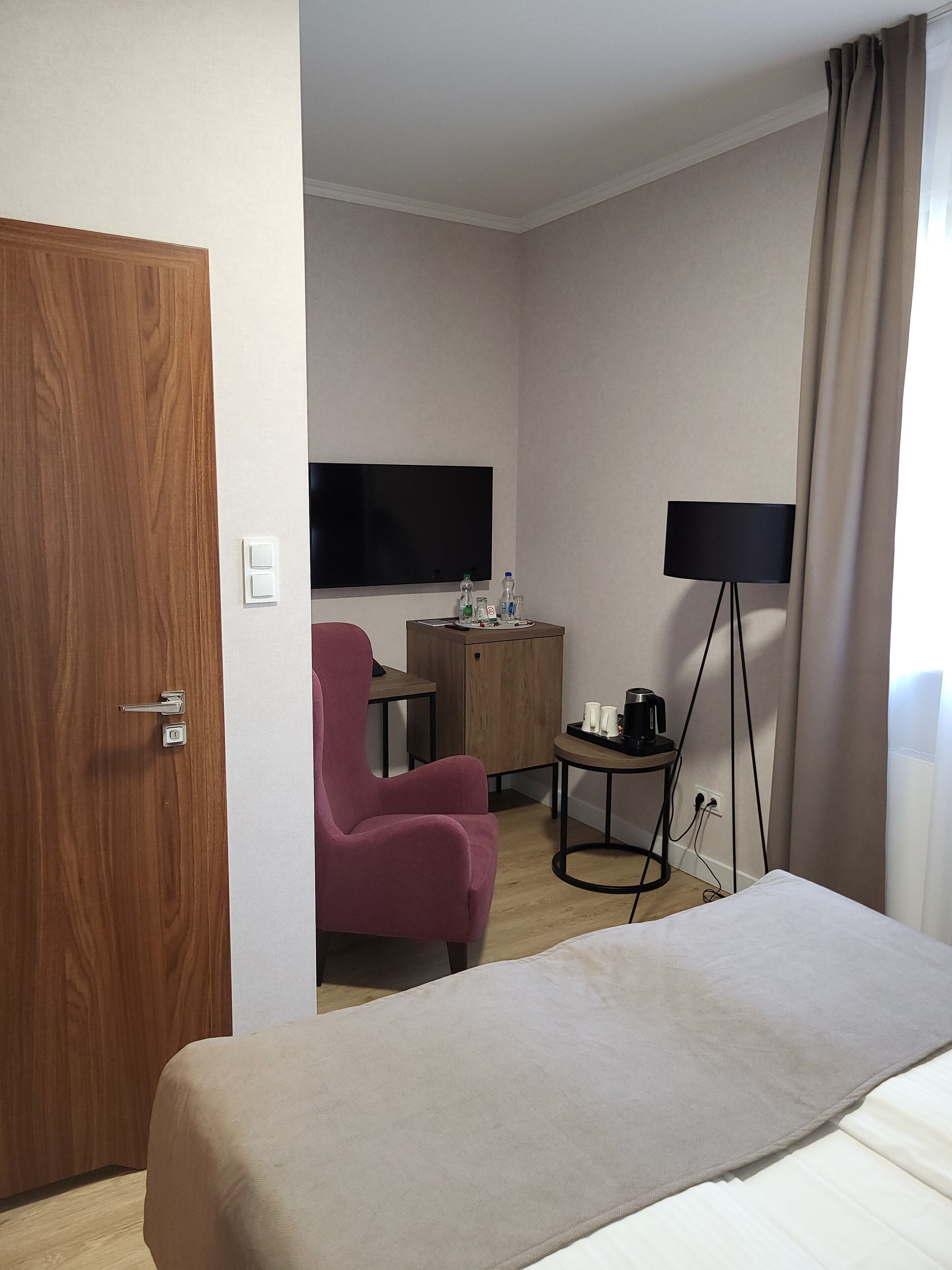 A hotel room with a bed, a desk with a computer, a chair, a television, and a coffee machine.