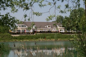A lakeside restaurant with outdoor seating and a view of the water. - Hotel Buenos (Geldrop)