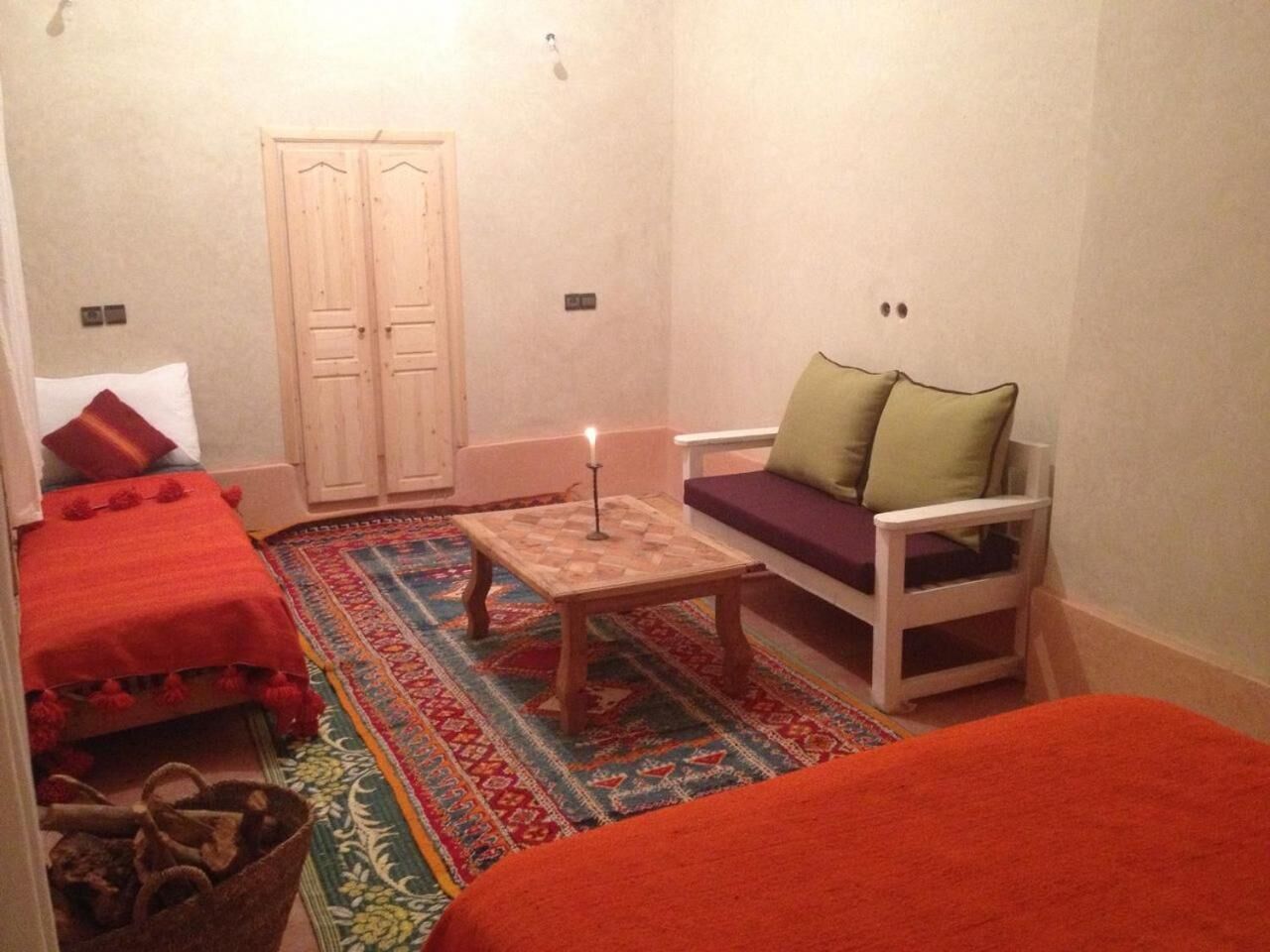 Une petite pièce accueillante avec deux lits, un canapé, une table avec une bougie et un tapis à motifs.