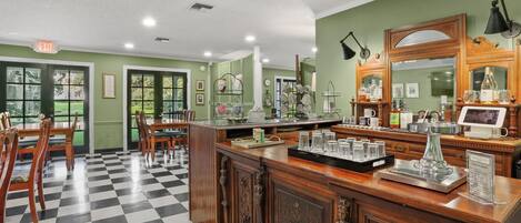 Un'hall d'albergo con pavimento a scacchi, arredi in legno, una reception e un grande specchio.
