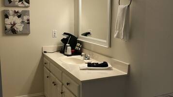 A bathroom with a white sink, a mirror, a towel rack, and two floral paintings on the wall.