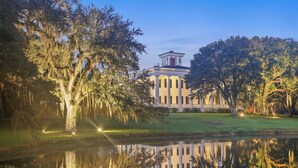 A stately building with a symmetrical facade, a central pediment, and a reflection in a calm body of water. - Greenwood Plantation B&B (St. Francisville)