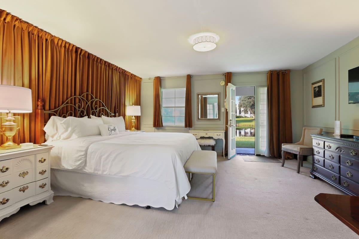 A bedroom with a large bed, bedside tables, a dresser, and a chair.