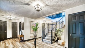 Un vestíbulo espacioso con piso de madera, una escalera y una puerta azul oscuro.