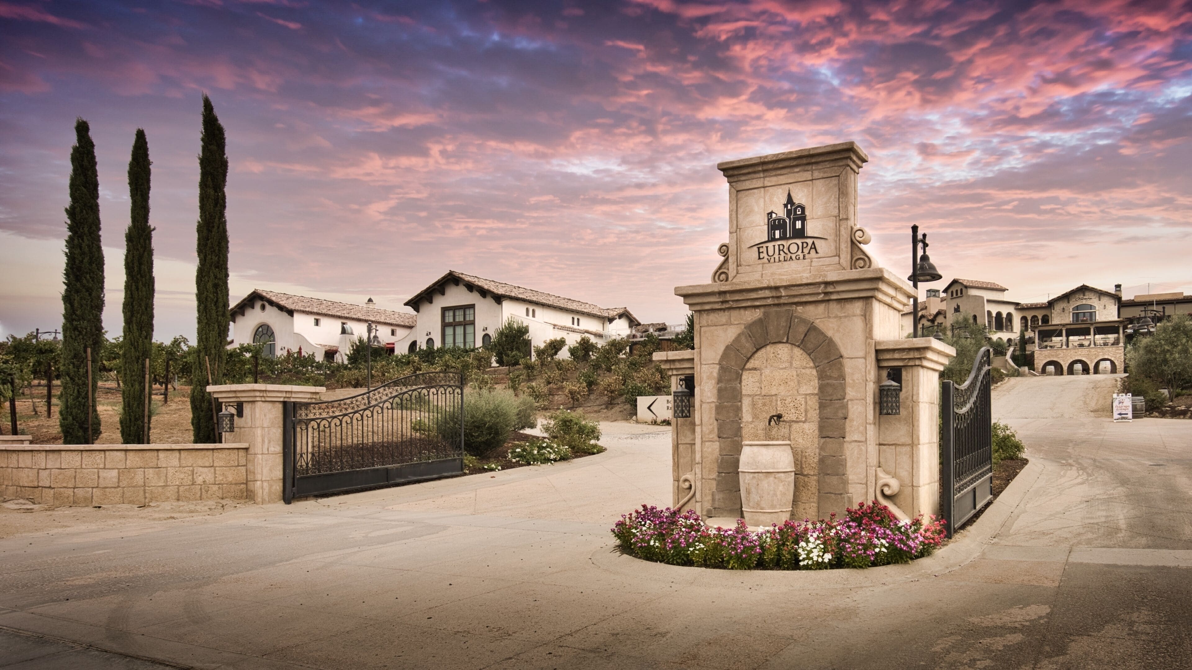 A gated entrance with a sign reading "EUROPA VILLAGE" and a stone archway.