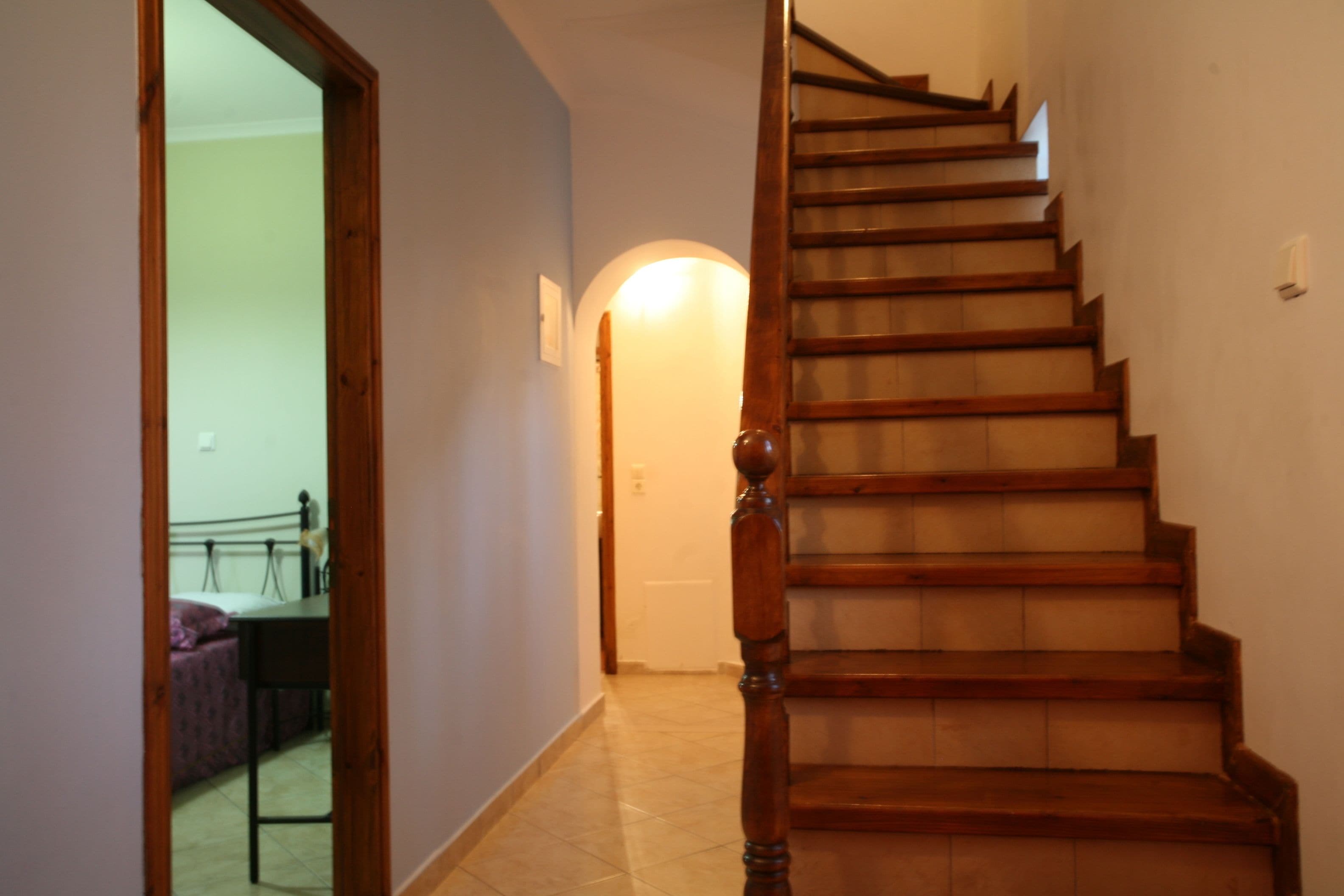 A wooden staircase with a handrail leading to an upper floor.