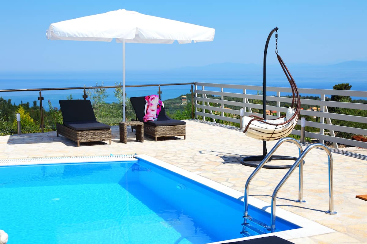 Un área de piscina con sillas de descanso y una silla colgante, con vistas a un paisaje.
