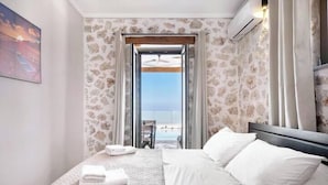 Une chambre d’hôtel avec un lit, une vue sur la plage et un mur en pierre.