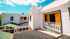 Un edifici blanc amb una porta groga i una tanca blanca de palets.