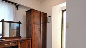 Habitació amb escriptori de fusta, un mirall gran i un armari.