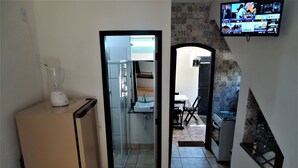 A kitchen with a refrigerator, a blender, a tiled backsplash, and a television mounted on the wall. - Vila do Sossego (Cabo Frio)