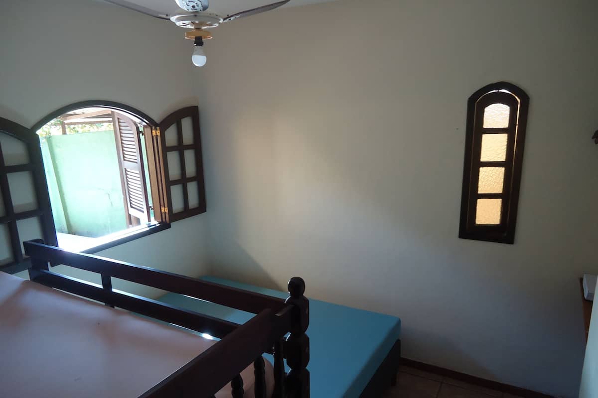 A bedroom with a single bed, a window, and a ceiling fan.