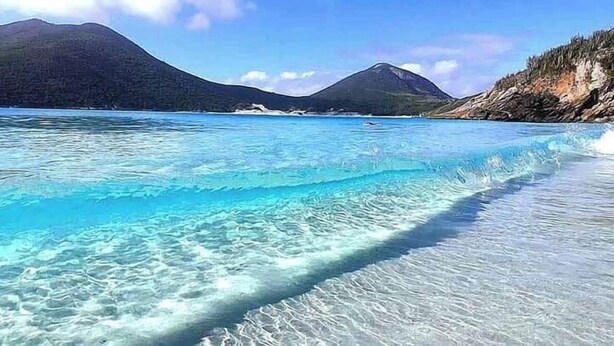 A beach with clear turquoise water and distant mountains. - Vila do Sossego (Cabo Frio)