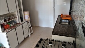 A compact kitchen with white cabinets, a gas stove, a sink, and a tiled backsplash. - Vila do Sossego (Cabo Frio)