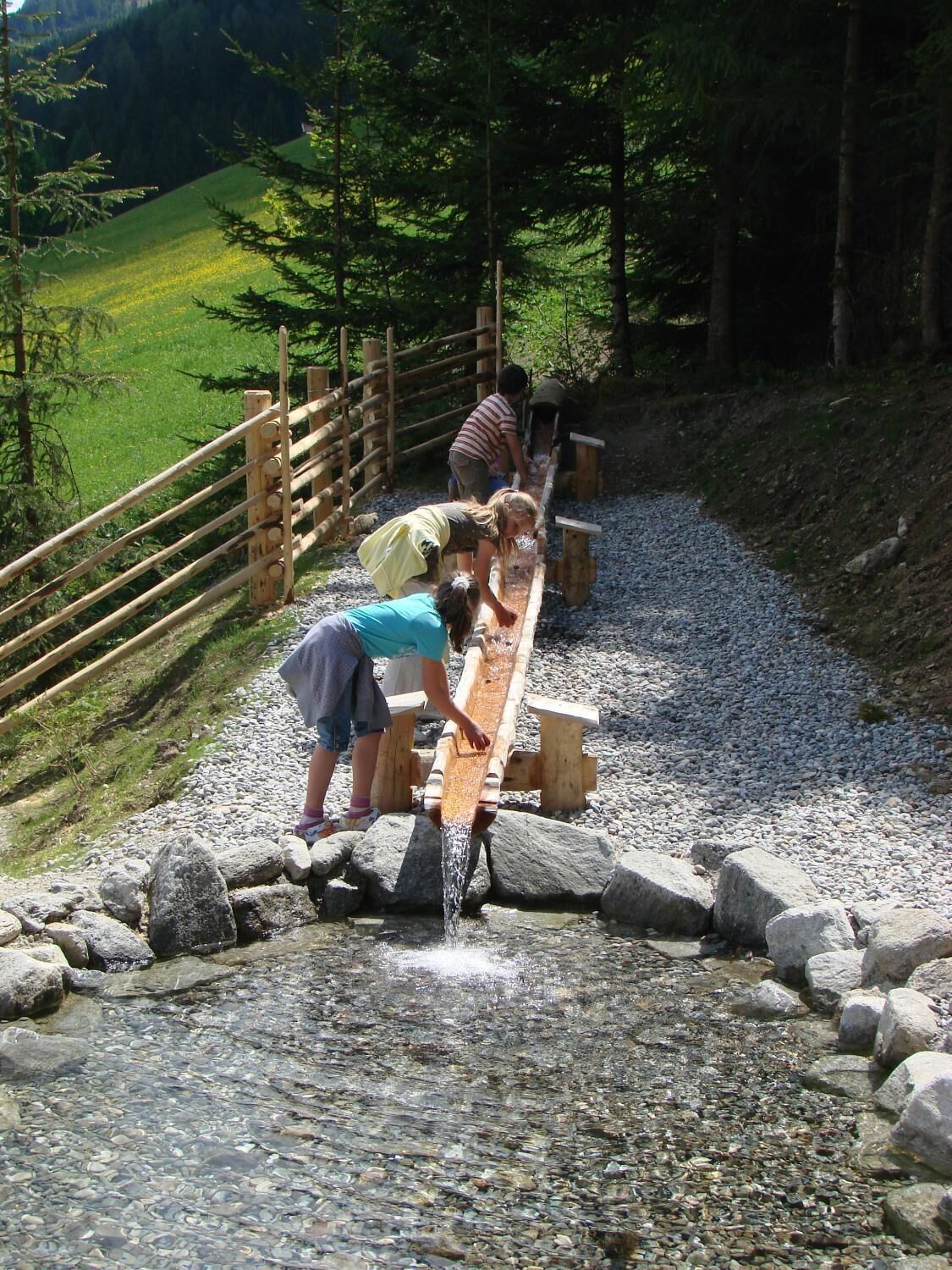 A wooden footbridge over a stream with people crossing.