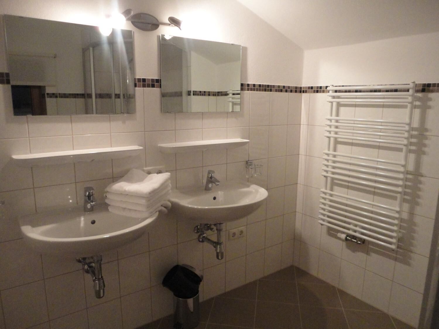 A bathroom with two sinks, a mirror, and a towel rack.
