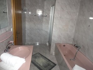 A bathroom with a marble floor, a shower, a sink, and a bathtub.