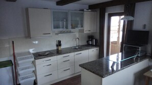 A modern kitchen with white cabinets, a granite countertop, and a built-in oven. - Apartments Klammerhof (Hainzenberg)