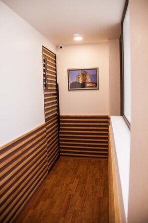 A narrow hallway with wooden paneling on the walls and a wooden floor.