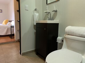 A compact bathroom with a toilet, sink, and towel rack.