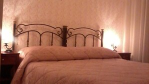 A neatly made bed with a quilted blanket and a metal headboard. There are two bedside tables with lamps. - B&B Michael (Monte Sant'Angelo)