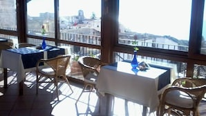 A restaurant with outdoor seating, large windows, and a view of the cityscape. - B&B Michael (Monte Sant'Angelo)