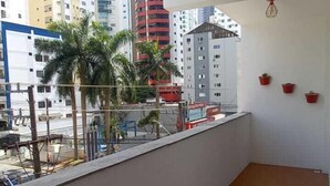 Un balcone con pavimento piastrellato, vista su una città con edifici alti e un lampadario a sospensione.