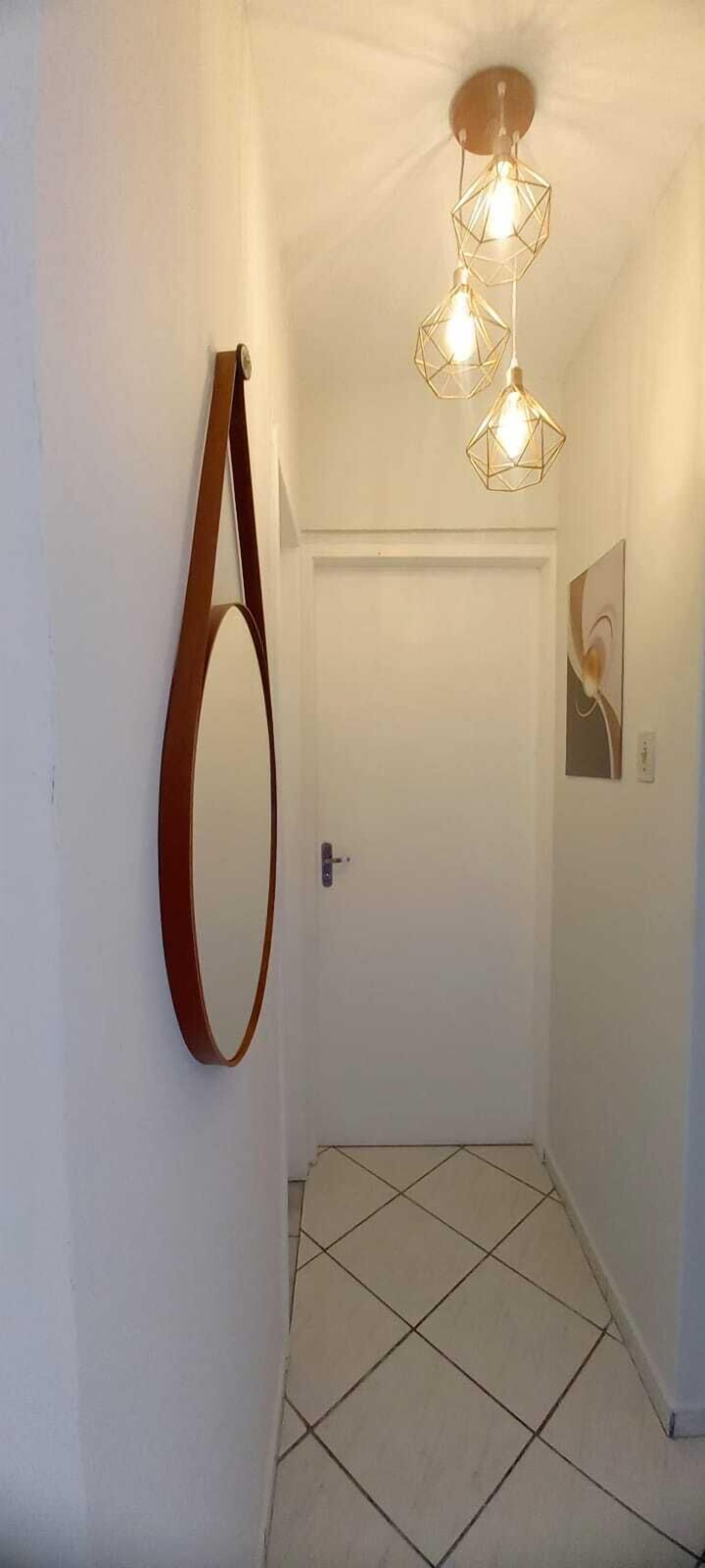 A hallway with a white door, a hanging mirror, and a geometric light fixture.