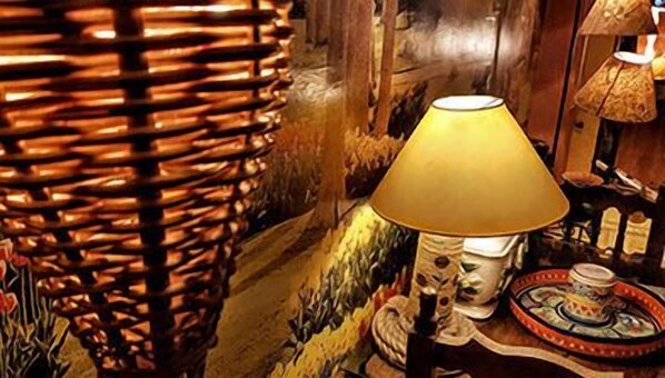 Una silla de mimbre, una mesa con una lámpara y un plato decorativo.
