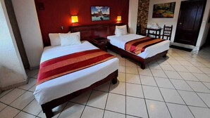 Quarto de hotel com duas camas, uma parede de destaque vermelha e um quadro sobre a cabeceira.
