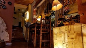 Interior acolhedor com móveis de madeira, escada e obras de arte decorativas.