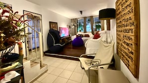 Una sala de estar con un sofá, un sillón, un asiento informal, un televisor y una decoración de pared.