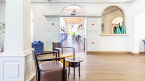 Un vestíbulo de hotel con una zona de estar central, una recepción y vistas al patio exterior.