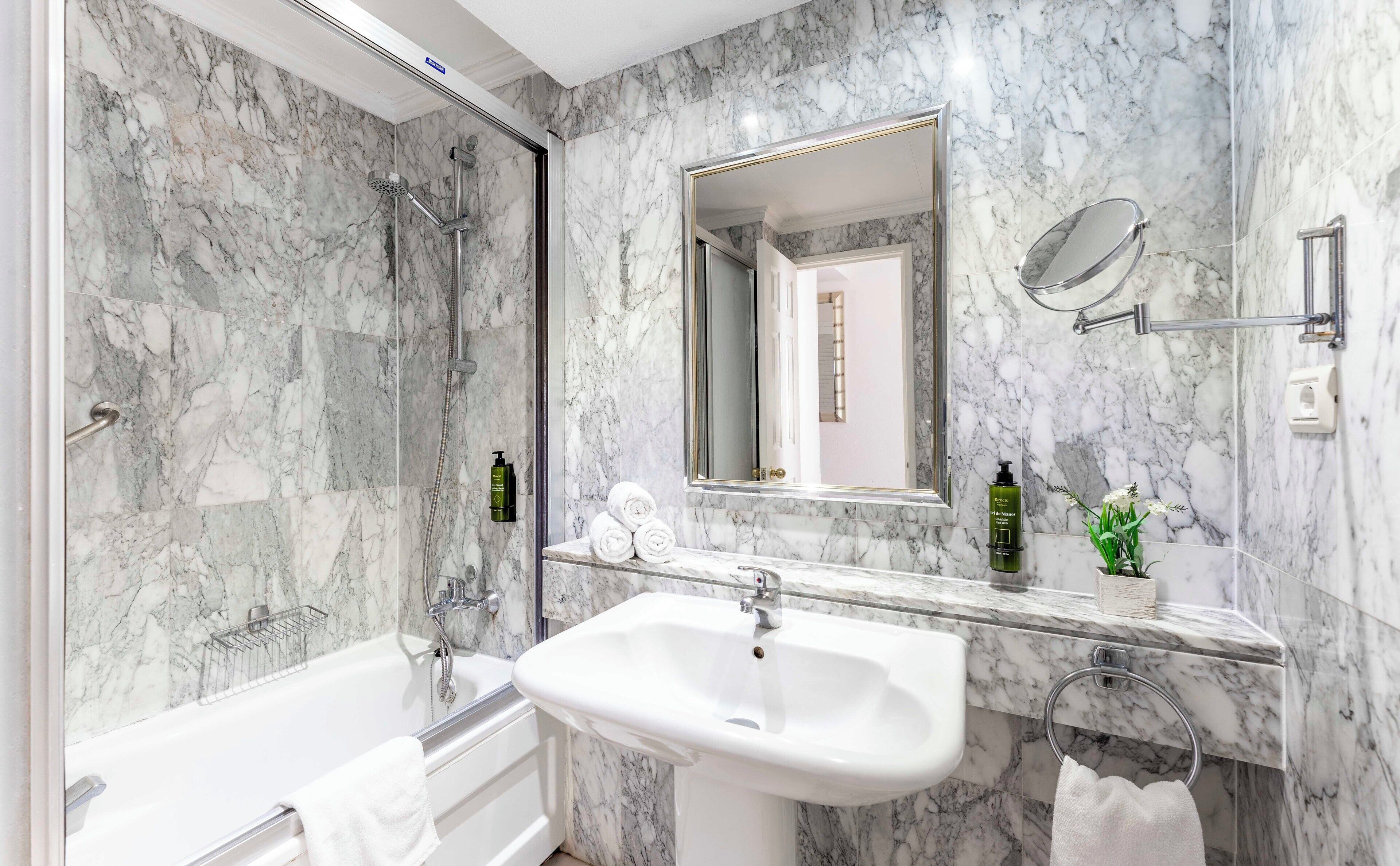 A bathroom with a bathtub, a sink, and a shower. There are towels and toiletries on the counter.