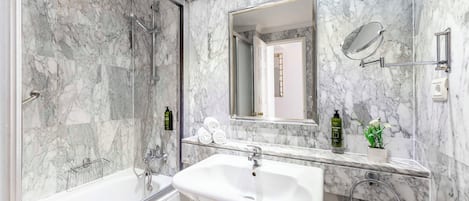 A bathroom with a bathtub, a sink, and a shower. There are towels and toiletries on the counter.