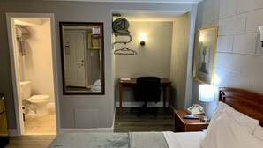 Una habitación de hotel con una cama, un escritorio, una silla, un teléfono y un espejo.