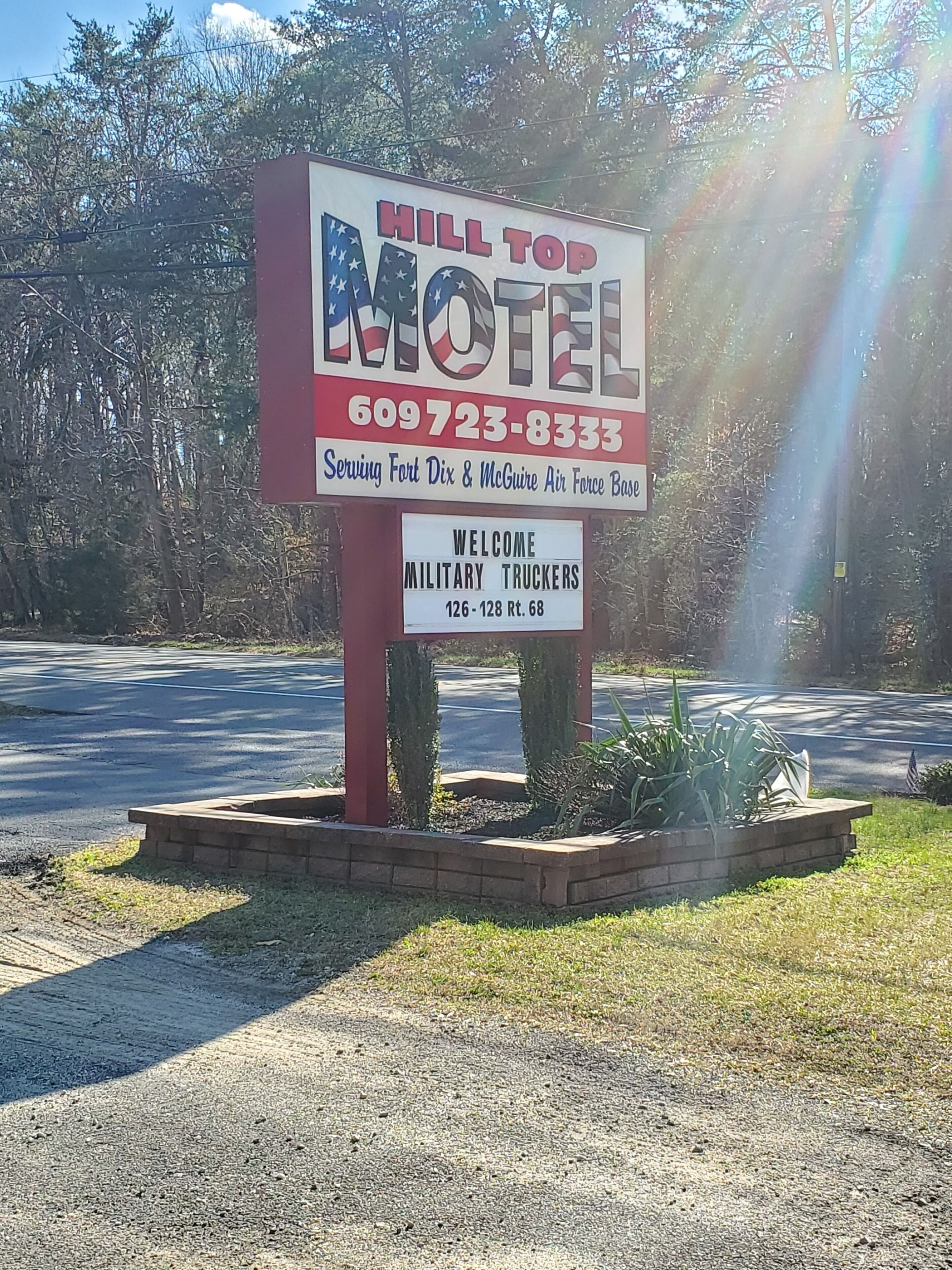 Et motel-skilt med navnet 'Hill Top Motel' og et telefonnummer. Velkomst til militærtruckførere, og nævner servering af Fort Dix & McGuire Air Force Base.