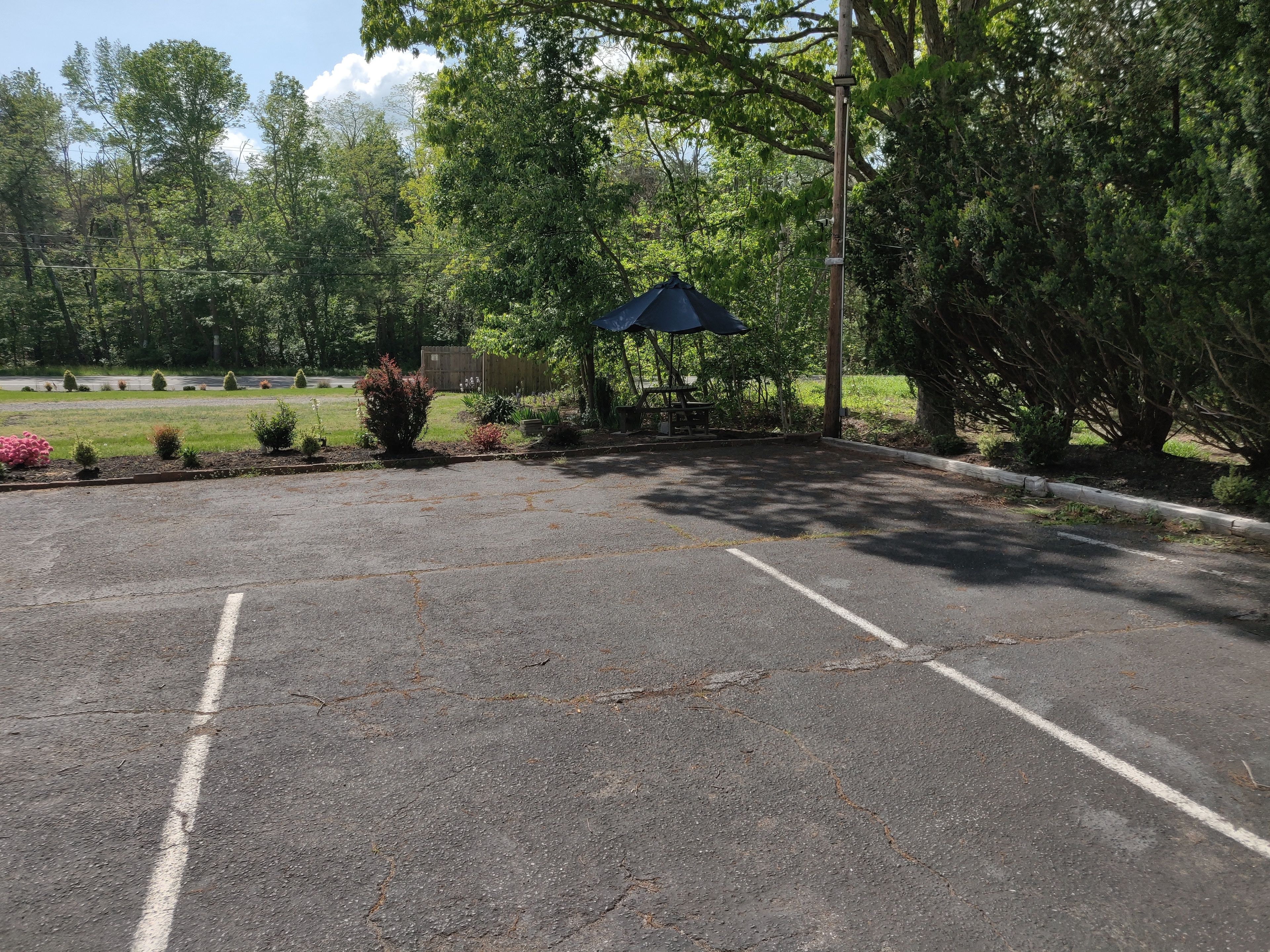 A parking lot with a blue canopy shelter, surrounded by greenery and trees.