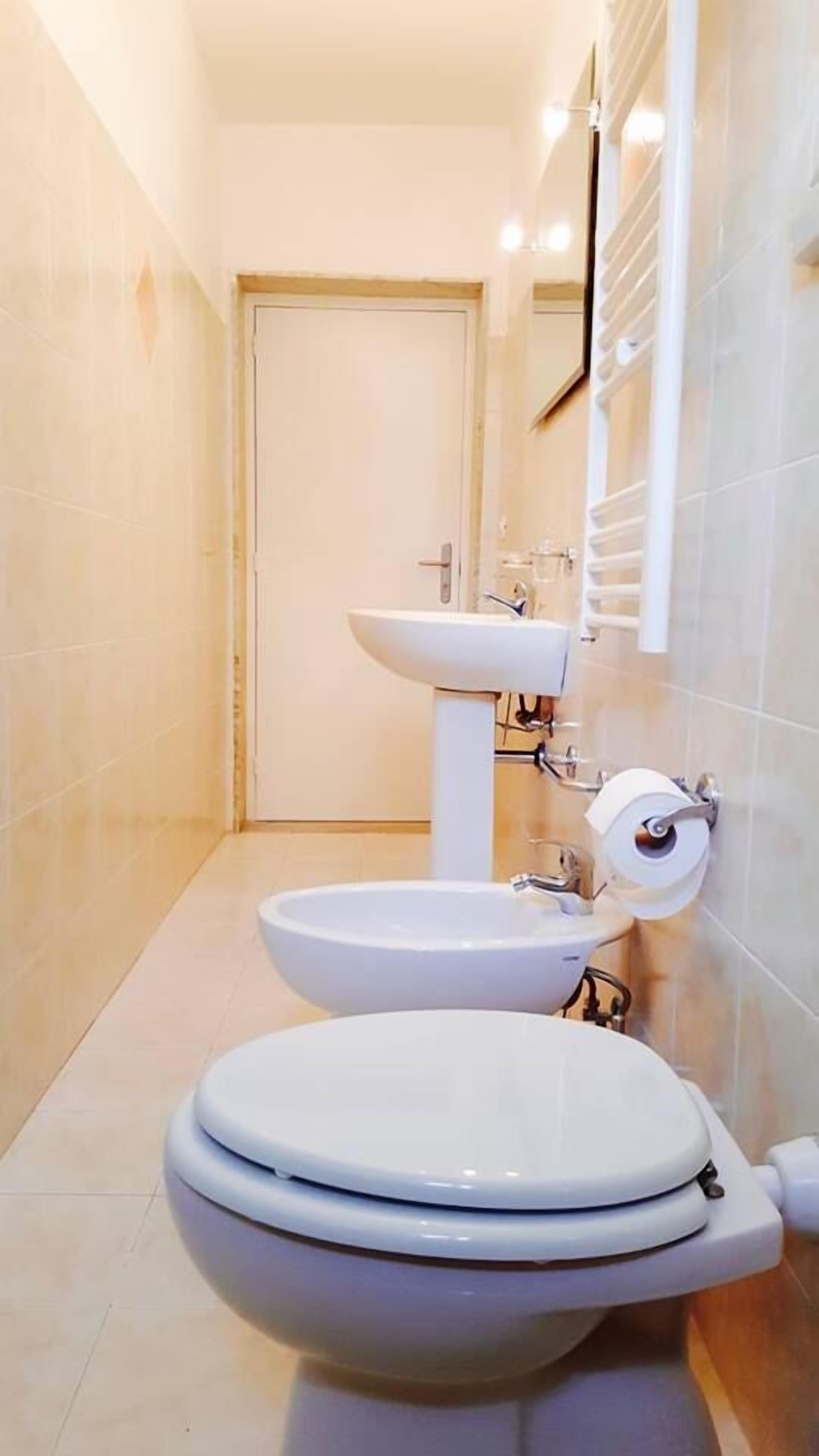 Une salle de bain équipée de toilettes, d’un lavabo et d’un porte-rouleau de papier toilette.