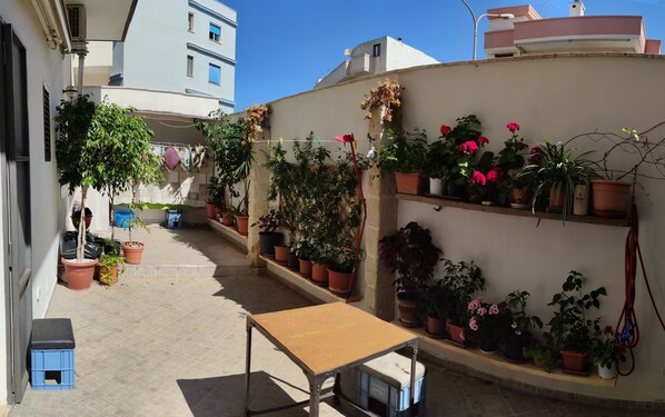 A narrow outdoor corridor with potted plants and a small table. - CASA della NONNA (Polignano a Mare)