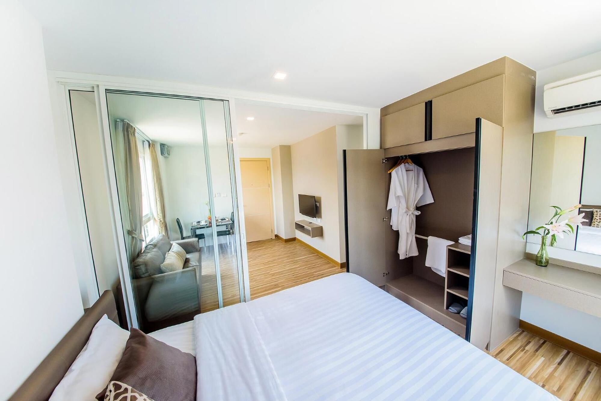 A modern hotel room with a large bed, a walk-in closet, a bathroom with a shower, and a television.