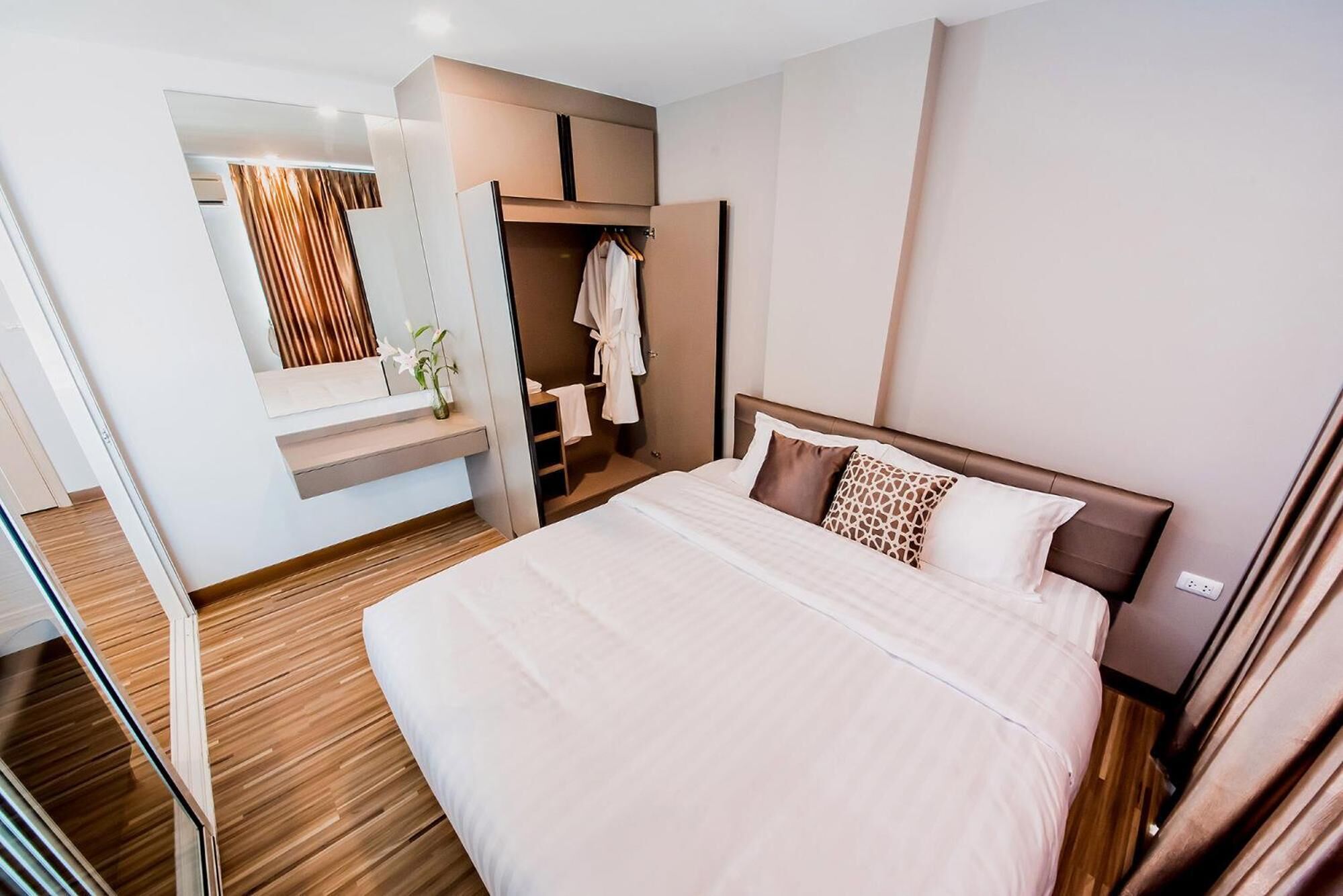 Een moderne hotelkamer met een groot bed, een inloopkast en een badkamer met spiegel en handdoekhouder.