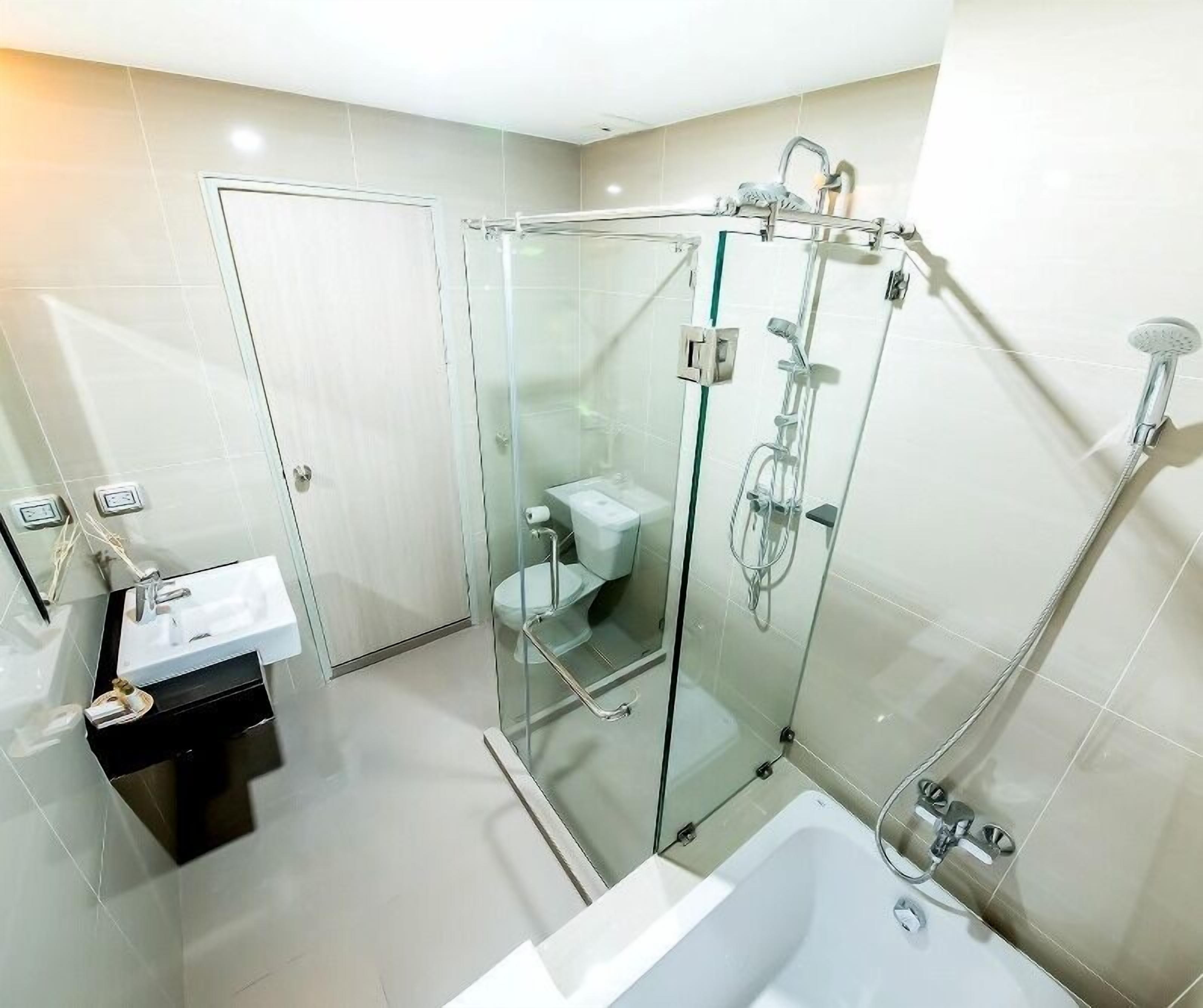 A modern bathroom with a glass-enclosed shower, a white sink, and a bathtub.