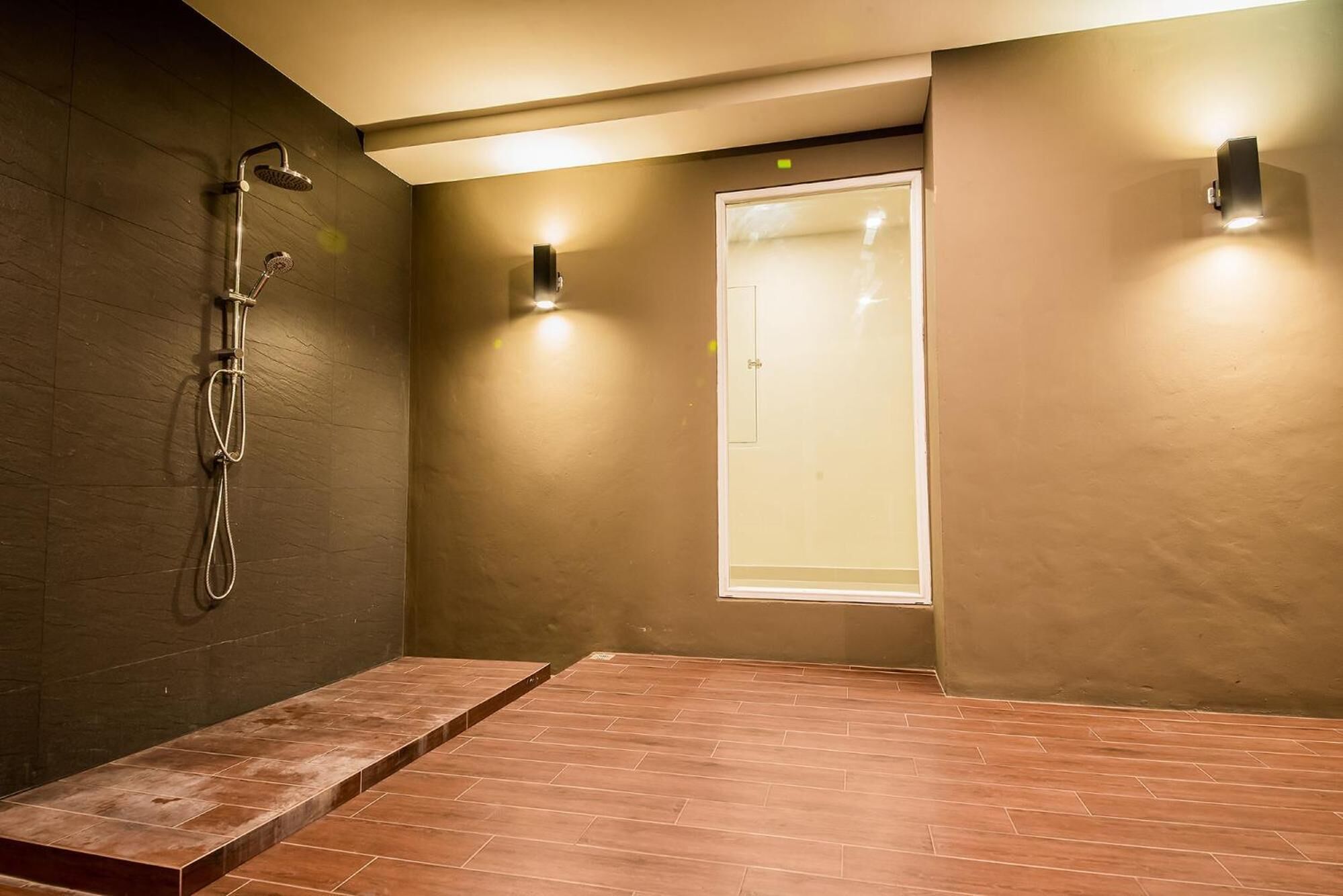 Un espacio de ducha moderno con puerta de vidrio, cabezal de ducha y un perchero para toallas.