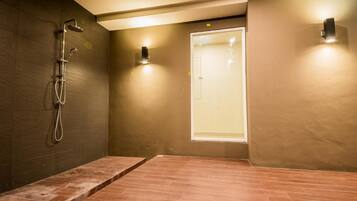 Un espacio de ducha moderno con puerta de vidrio, cabezal de ducha y un perchero para toallas.