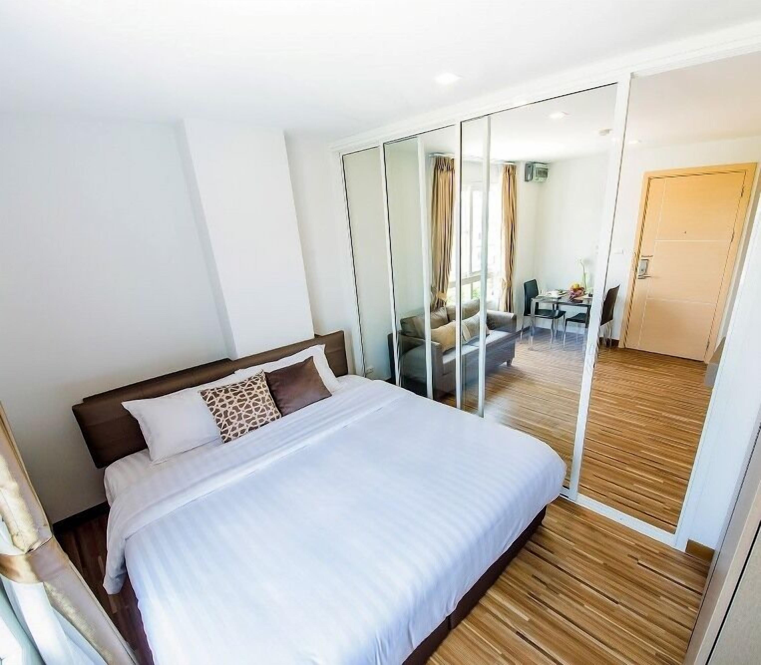 Een hotelkamer met een groot bed, een glazen scheiding en uitzicht op een eetruimte.