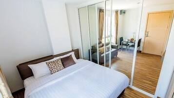 Een hotelkamer met een groot bed, een glazen scheiding en uitzicht op een eetruimte.